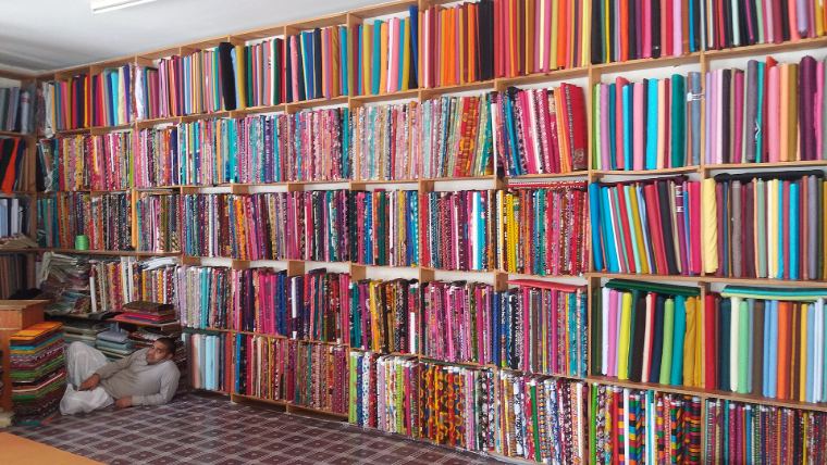 A wall of folded fabrics in every colour in a cloth shop